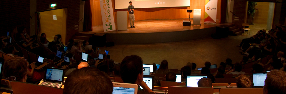 Photo of a talk at GUADEC 2010, with speaker talking and several attendees with laptops